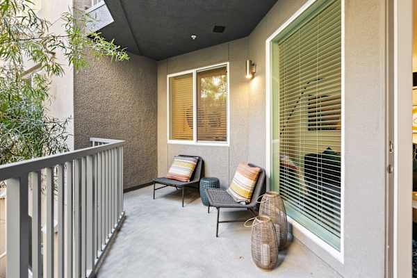 a balcony with two chairs and a window with blinds